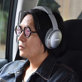 車内で、QC35IIを着ける小林紀晴