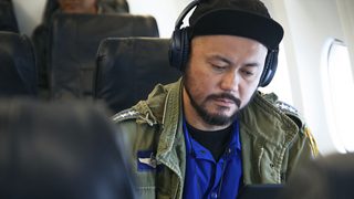 飛行機内でQC35 IIを着ける山根敏史