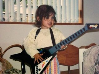 Janay Harding as a child playing with a guitar