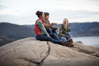 Des amis assis sur un rocher au bord d’un lac