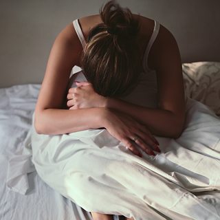 Mujer cansada y sentada en el borde de una cama después de despertarse