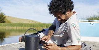 Homme écoutant une enceinte Bose Portable Home Speaker sur un quai