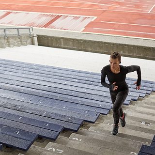 Mujer corriendo por los escalones de un estadio utilizando los audífonos inalámbricos SoundSport Free