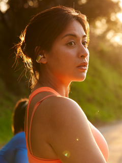 Femme se préparant à courir et portant des écouteurs oreilles libres Bose Ultra