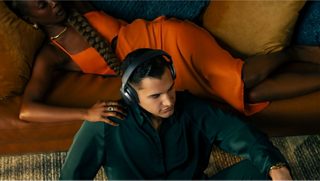 Un homme assis par terre dans son salon avec le casque Bose QuietComfort Ultra sur la tête