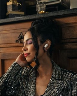 Eine Frau in einer Küche, die nach einer Weihnachtsfeier Musik über die Bose QuietComfort Ultra Earbuds hört