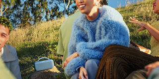 Young people gathered outside listening to music from a Bose SoundLink Max Portable Speaker