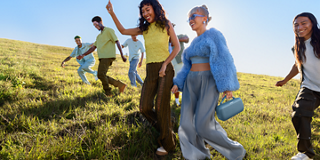 Young people walking through a field carrying a Bose SoundLink Max Portable Speaker