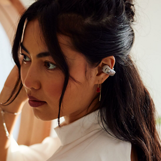 A woman putting on her Bose Ultra Open Earbuds.