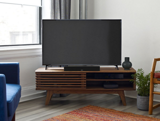 Un téléviseur et une barre de son intelligente Bose placés sur une console TV, dans un salon.