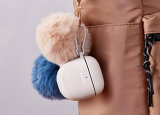 Silikonowe etui do słuchawek Bose Quietcomfort Earbuds II w kolorze Soapstone przyczepione do torby