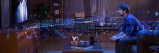 Homme dans un salon regardant la télévision avec des ondes sonores émanant du système d’enceintes, illustrant l’effet de la technologie Dolby Atmos