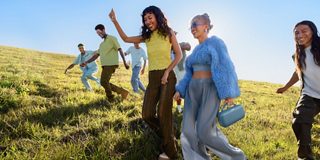 Friends walking through a field listening to a Bose SoundLink Max Portable Speaker.