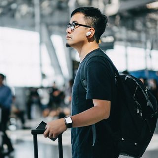 Man wearing Bose QuietComfort Earbuds in an airport terminal