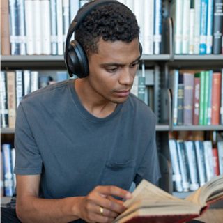Man wearing Bose Noise Cancelling Headphones 700 in a library