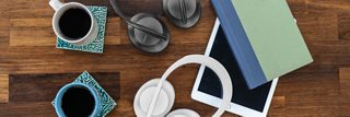 Deux casques Bose Noise Cancelling Headphones 700, l’un noir, l’autre en édition Luxe Argent, posés sur une table avec des cafés, un livre et une tablette