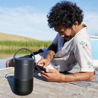 Homme sur un ponton écoutant de la musique sur une enceinte Bose Portable Smart Speaker