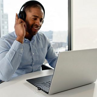 A man using Bose Noise Cancelling Headphones 700 UC from his laptop for a conference call