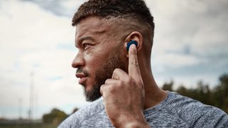 Man accessing Spotify by double-tapping the left earbud