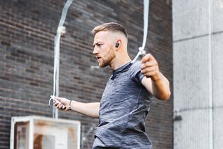 Hombre saltando a la comba con los Bose Sport Earbuds en Triple Black puestos