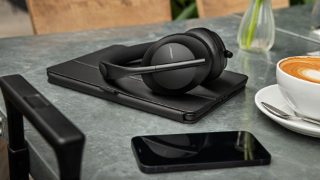 Bose Noise Cancelling Headphones 700 on a table with a tablet and a smartphone