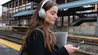 Una mujer escuchando música en su teléfono con los audífonos Bose Noise Cancelling Headphones 700