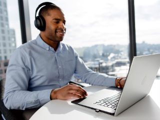 A man using Bose Noise Cancelling Headphones 700 UC from his laptop for a conference call