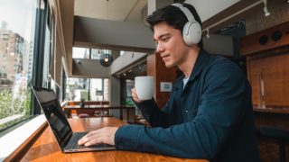 Man wearing Bose QuietComfort 45 headphones while working on a laptop