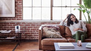 Kvinna sitter i en soffa och lyssnar på en Bose Home Speaker 500