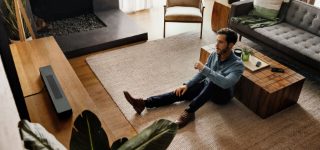 Man watching TV in a living room with a Bose Smart Soundbar 600