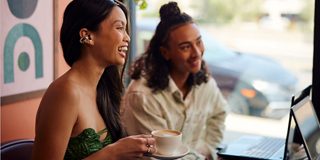 Mensen die in een café vergaderen en Bose Ultra open oordopjes dragen