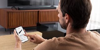 Homme ajustant le volume de la barre de son intelligente Bose 900 avec l’application Bose 