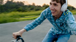 Mężczyzna w słuchawkach Bose QuietComfort 45 Headphones jadący na rowerze