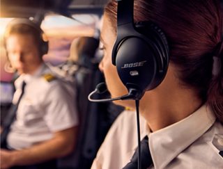 Side view of a commercial pilot’s face and her Bose A30 Aviation Headset as she turns and talks to her copilot