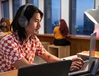 Hombre trabajando en una oficina con los Bose QuietComfort 45 Headphones