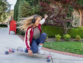 Woman skateboarding wearing Bose QuietComfort SE headphones
