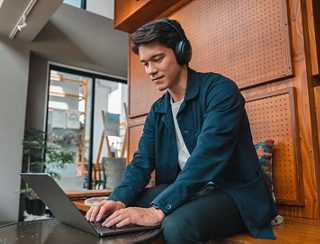 Man working in an office wearing Bose QuietComfort SE headphones