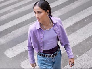 Woman wearing Bose Ultra Open Earbuds walking across the street outside.