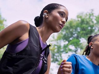 Woman wearing Bose Ultra Open Earbuds while going for a run.