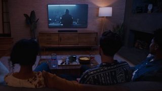 Couple watching TV with a Bose Smart Soundbar on a TV console.