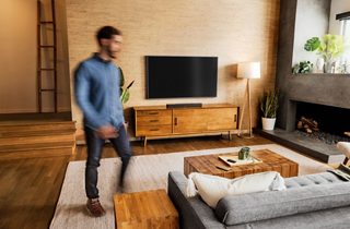 Man in a living room with a TV and Bose Smart Soundbar 600