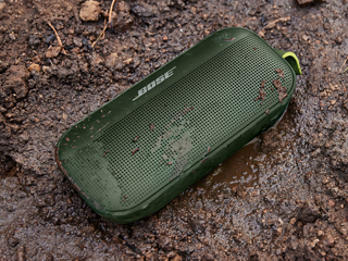 Cypress Green SoundLink Flex Bluetooth Speaker on the ground with water and mud on it